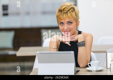 Lächelnde Geschäftsfrau saß am Schreibtisch mit Computer Stockfoto