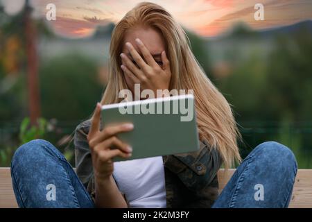 Eine peinliche oder schüchterne junge Frau, die ihr Gesicht verdeckt Stockfoto