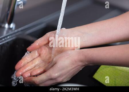 Junge Frau wascht ihre Hände in einem Waschbecken Stockfoto