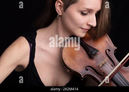 Schöne Frau, die Violinstudio-Porträt auf Schwarz spielt Stockfoto