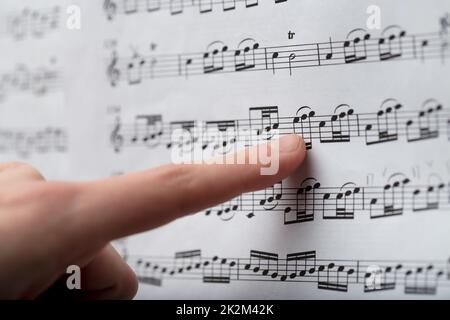 Weiblicher Finger, der den Noten eines Musikwertes folgt Stockfoto