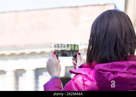 Frau in einer Stadt, die Fotos mit einem durchsichtigen Handy macht Stockfoto