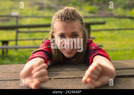 Eine Frau, die Arme über einen Tisch streckt und im Park gähnt Stockfoto