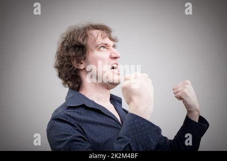 Böser Mann, der Wut mit Gesicht und Händen ausdrückt Stockfoto