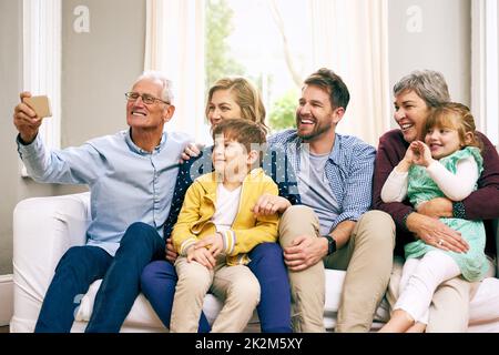 Dies ist unsere große und schöne Familie. Aufnahme einer Familie mit mehreren Generationen, die zu Hause auf dem Sofa sitzt. Stockfoto
