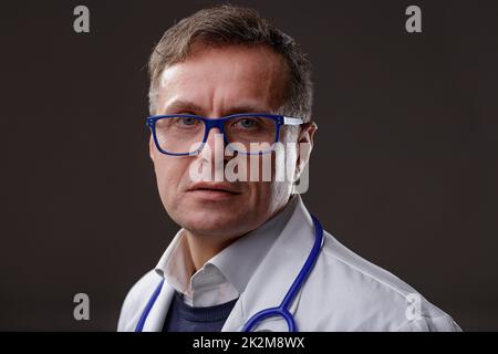 Männlicher Arzt oder Krankenschwester mittleren Alters mit intensivem Ausdruck Stockfoto