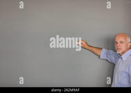 Seriöser Senior-Lehrer oder Dozent an der Tafel Stockfoto