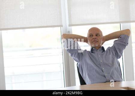 Geschäftsmann entspannend mit Händen hinter dem Kopf Stockfoto