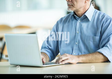 Ein Geschäftsmann im Hemd, der an einem Laptop arbeitet Stockfoto