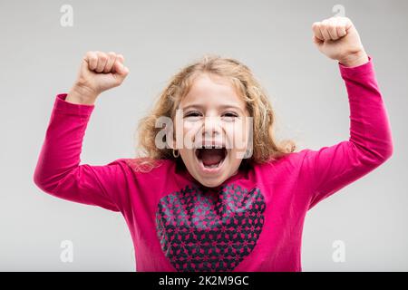 Lachendes, junges Schulmädchen, das die Hand hebt Stockfoto