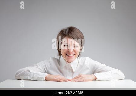 Eine Frau, die auf grauem Hintergrund lacht Stockfoto