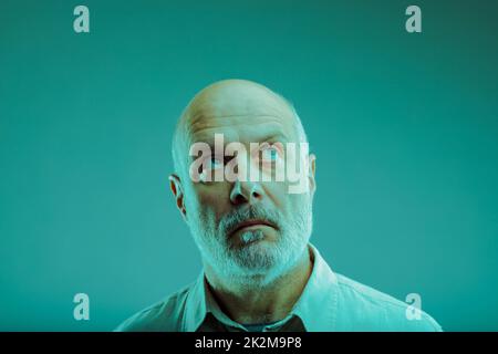 Ein bärtiger Mann, der tief in Gedanken nach oben blickt Stockfoto