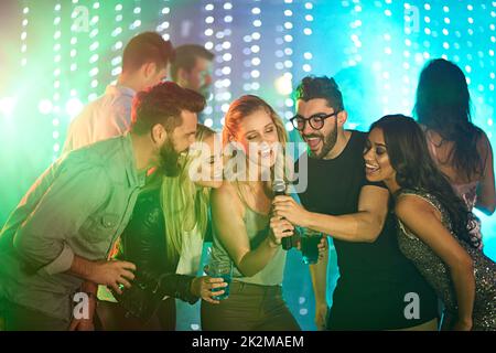 Es gibt einen Superstar in uns allen. Aufnahme einer Gruppe von Freunden, die auf einer Party Karaoke singen. Stockfoto