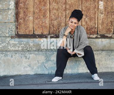 Ändern Sie die Mode, um Sie zu passen. Ganzkörperaufnahme einer modischen jungen Frau, die draußen sitzt. Stockfoto