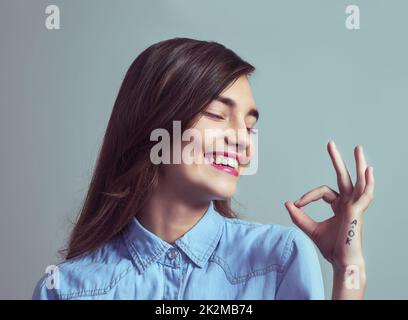 Alles ist in Ordnung. Studioaufnahme einer attraktiven jungen Frau, die mit der Hand vor grauem Hintergrund ein A-Okay-Zeichen macht. Stockfoto