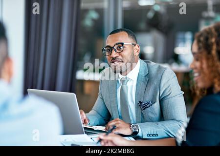 Hören Sie aufmerksam zu. Eine kleine Aufnahme eines hübschen jungen Geschäftsmanns, der während einer Sitzung im Sitzungssaal an seinem Laptop arbeitet. Stockfoto