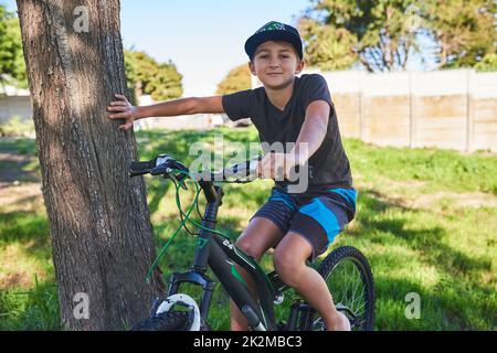 Will reiten. Beschnittenes Porträt eines Jungen, der draußen mit dem Fahrrad unterwegs ist. Stockfoto