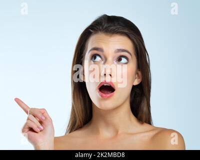 Das hat sie überrascht. Studioaufnahme einer schönen jungen Frau, die schockiert vor blauem Hintergrund aussieht. Stockfoto