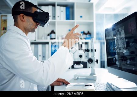 Die Zukunft ist den Progressiven vorbehalten. Aufnahme eines Wissenschaftlers, der ein Virtual-Reality-Headset verwendet, während er in einem Labor forscht. Stockfoto