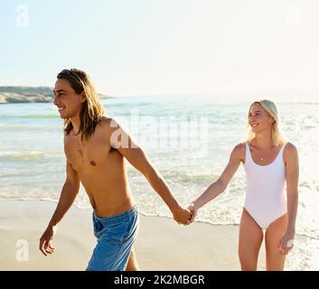Ich möchte mit euch durch das Leben schlendern. Aufnahme eines jungen Paares, das eine gute Zeit zusammen am Strand genießt. Stockfoto