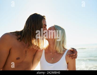 Wirklich lieben heißt wirklich leben. Aufnahme eines liebevollen jungen Paares, das sich am Strand küsst. Stockfoto