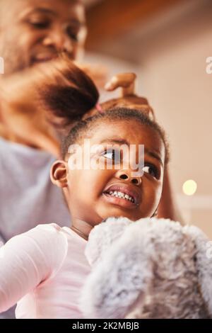 Weiß er, was er tut? Aufnahme eines jungen Vaters, der seine Töchter zu Hause Haare macht. Stockfoto
