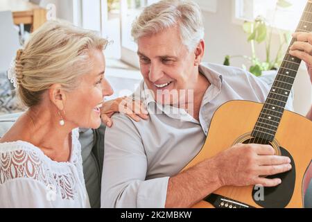 Seniorenpaar mit Gitarre für Musik und gemeinsames Singen auf dem Sofa für den Ruhestand und Sommerlinsenfackel. Glückliche ältere Frau oder kreativ Stockfoto