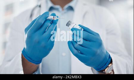 Die nächste Dosis wird vorbereitet. Zugeschnittenes Bild eines nicht erkennbaren männlichen Arztes, der die covid 19-Impfung für einen Patienten vorbereitet. Stockfoto