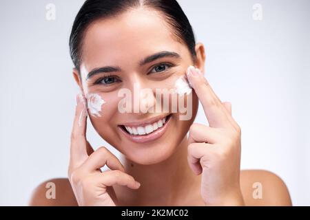 Die richtige Reinigungslösung für Sie zu finden, ist ein Prozess der Erprobung. Aufnahme einer schönen jungen Frau, die ihr Gesicht mit einer Feuchtigkeitscreme versorgt. Stockfoto