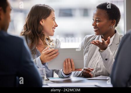 Ich verstehe genau, was Sie meinen. Aufnahme von zwei jungen Geschäftsfrauen, die im Büro sitzen und sich mit einem digitalen Tablet unterhalten. Stockfoto