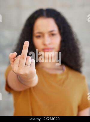 Meine Einstellung hängt davon ab, wie du mich behandelst. Ausgeschnittene Aufnahme einer jungen Frau, die ihren Mittelfinger zeigt, während sie draußen steht. Stockfoto