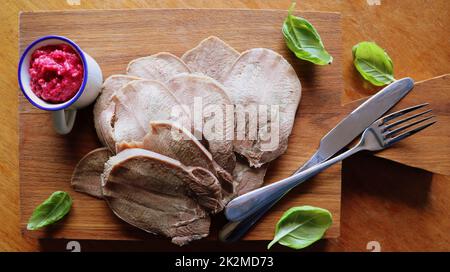 Rinderzunge serviert Meerrettichsauce und Basilikum auf Schneidebrett. Saftiges, zartes Fleisch eine tolle Vorspeise. Draufsicht Stockfoto