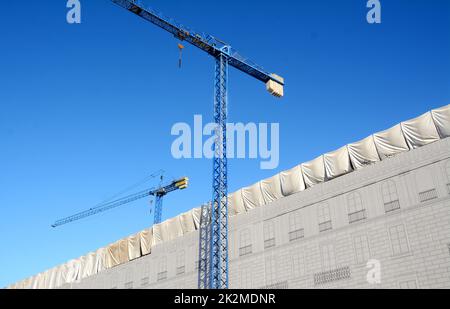 Große und hohe Baukräne mit Blick auf einen Palast. Stockfoto