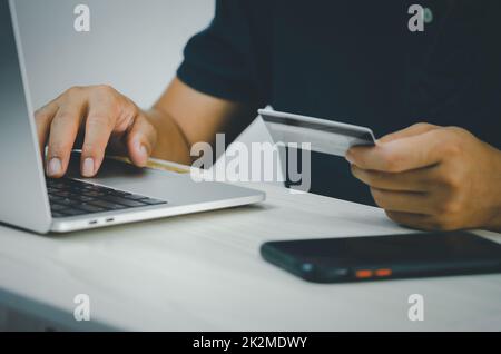 Männliche Hände auf der Computertastatur, die Finanz- und Kreditkartentransaktionen oder Online-Shopping im Internet macht. Stockfoto