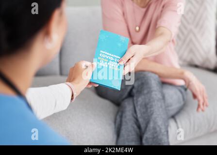 Erziehen Sie sich selbst. Aufnahme einer Krankenschwester, die ihrem Patienten eine Covid-19 Informationsbroschüre gab. Stockfoto