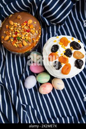 Ostereier und Osterkuchen liegen auf einer gestreiften blauen Schürze. Das Konzept der Osterfeiertage. Stockfoto