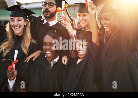 Unsere Eltern sind so stolz auf uns. Aufnahme einer Gruppe fröhlicher Studenten am Abschlusstag. Stockfoto