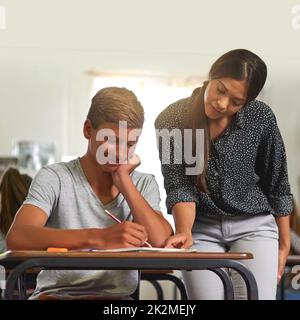 Zeigt ihm, wie es funktioniert hat. Aufnahme einer jungen Lehrerin, die einer Schülerin in ihrer Klasse etwas erklärt. Stockfoto