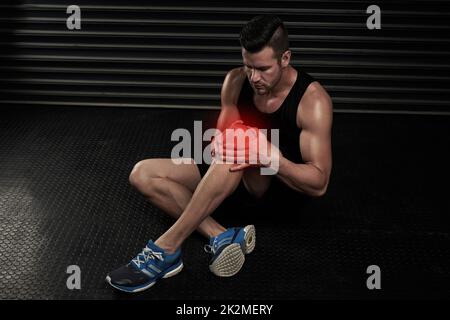 Immer noch Schmerzen am Knie Aufnahme eines sportlichen jungen Mannes, der im Studio mit einer Verletzung arbeitet. Stockfoto