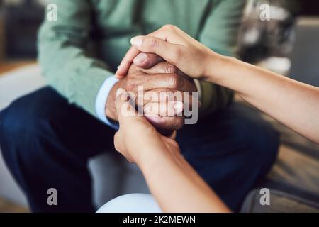 Ihre Unterstützung bedeutet mir alles. Aufnahme eines nicht erkennbaren älteren Mannes, der sich mit seiner Tochter die Hände hielt, während er zu Hause auf einer Couch saß. Stockfoto