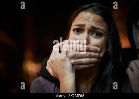 Wehrlos und in Gefahr. Porträt einer verängstigten jungen Frau mit ihren Angreifern über ihren Mund. Stockfoto