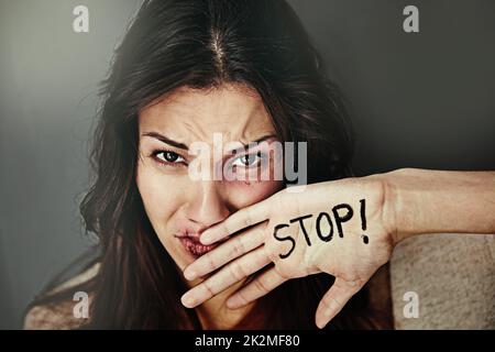 Es ist an der Zeit, dem häuslichen Missbrauch ein Ende zu setzen. Porträt einer verprügelten und gequetschten jungen Frau mit dem Wort STOP auf der Hand. Stockfoto