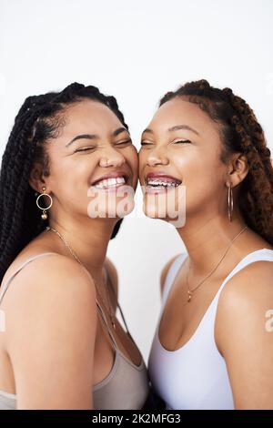 Lachen ist schön. Studioaufnahme von zwei schönen jungen Frauen, die vor einem grauen Hintergrund posieren. Stockfoto