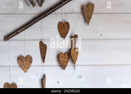 Ornamente in Form von Herzen. Hölzerne Ornamente auf den Ästen. Herzen aus Holz geschnitten. Herbstthema. Stockfoto