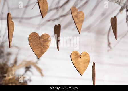 Ornamente in Form von Herzen. Hölzerne Ornamente auf den Ästen. Herzen aus Holz geschnitten. Herbstthema. Stockfoto
