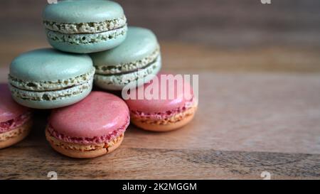 Grüne und rosafarbene Macarons auf einem hölzernen Hintergrund Stockfoto