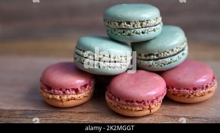 Grüne und rosafarbene Macarons auf einem hölzernen Hintergrund Stockfoto