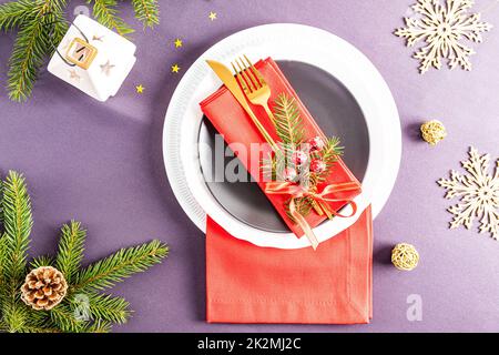 Schönes, modernes Design der Weihnachtsplatte. Rote Servietten gefaltet in einem Fächer mit Dekorationen auf weißen und dunklen Tellern Stockfoto