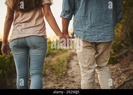 Wir bauen auf und wachsen zusammen. Nicht erkennbare Aufnahme eines Paares, das durch seine Ernte geht und dabei die Hände hält. Stockfoto