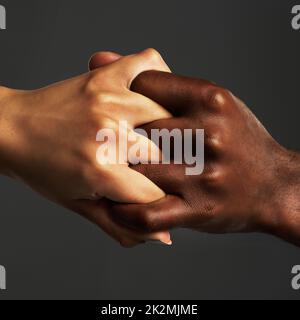 Waren für immer miteinander verbunden. Studioaufnahme von zwei nicht erkennbaren Personen, die ihre Hände vor grauem Hintergrund zusammenhalten. Stockfoto